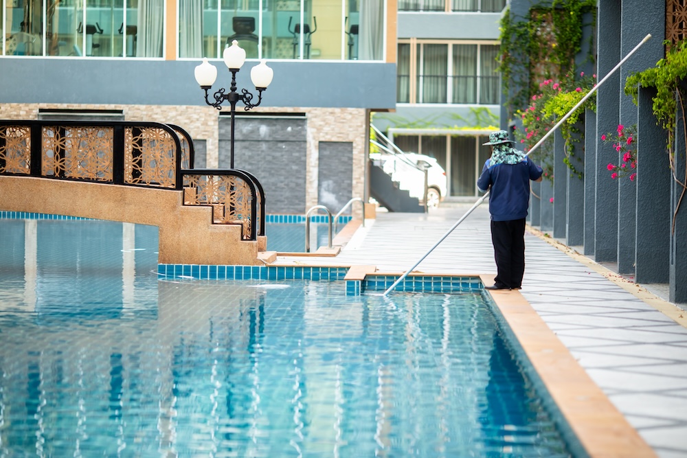 Staff are cleaning the hotel pool using an underwater vacuum pump. Pool Cleaning Service