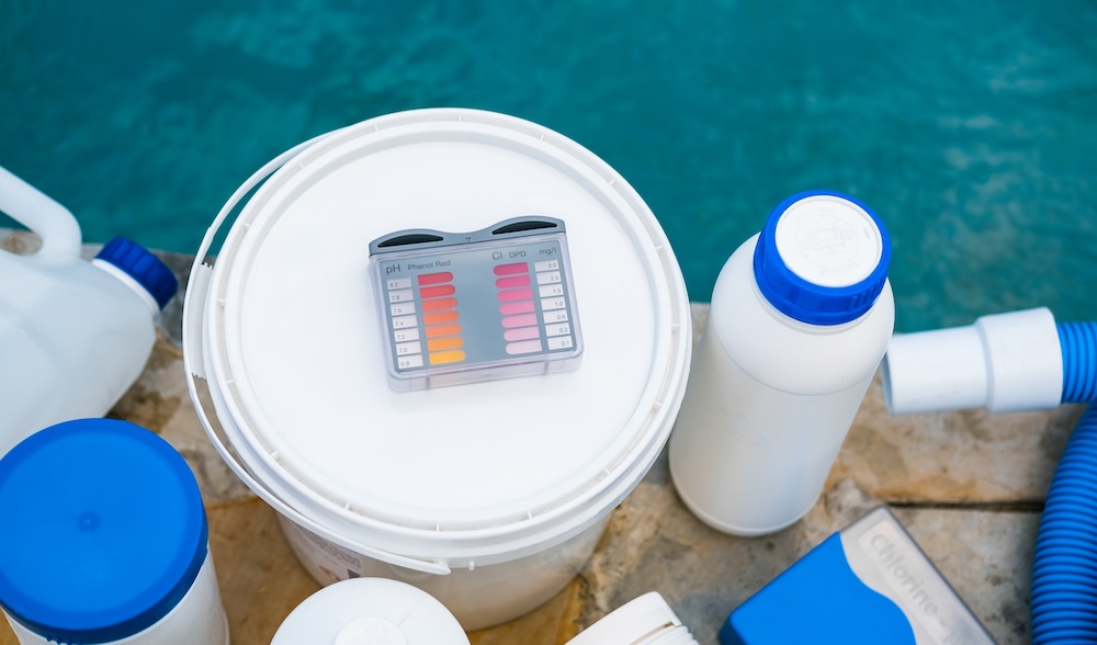 High angle view of equipment for testing the quality of pool water and chemical cleaning products at the edge of swimming pool.