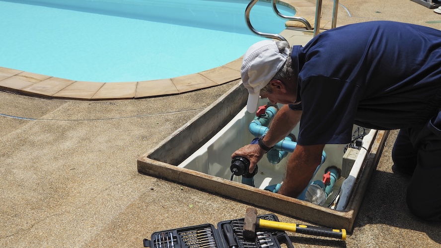 Technician fixing swimming pool water pump. Service and maintenance for swimming pool.