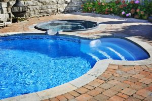 Outdoor inground residential swimming pool in backyard with hot tub