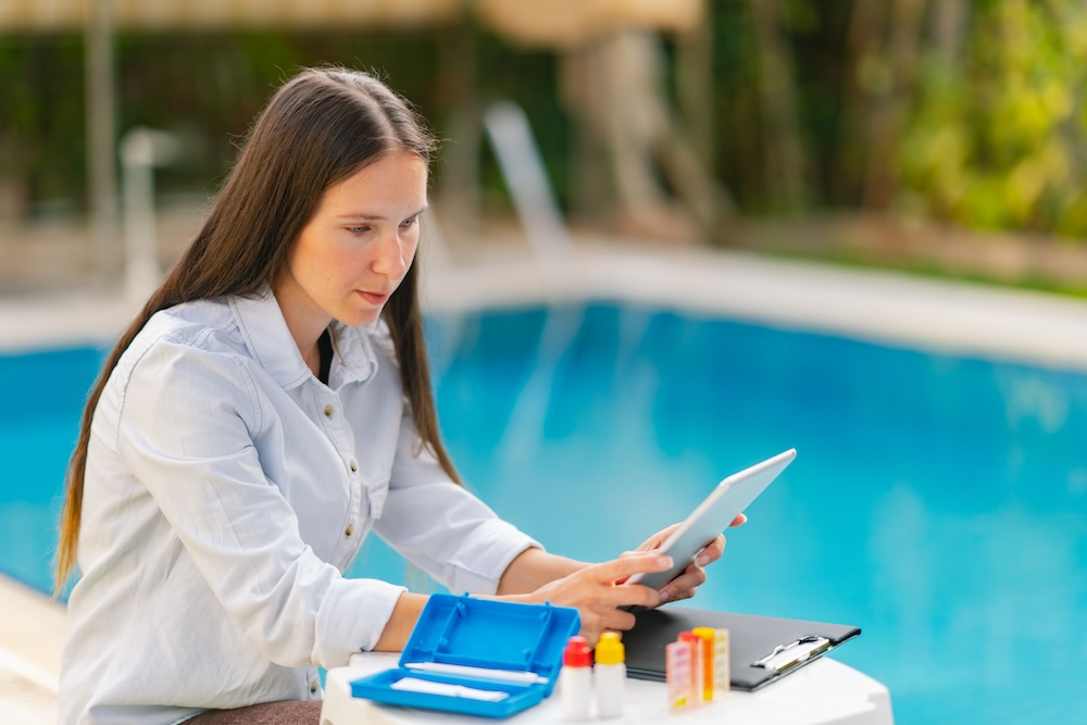 A female worker is checking the quality of a swimming pool.